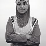 Eine junge Frau mit Kopftuch und zartem Lächeln auf den Lippen