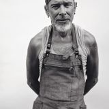 Ein alter Mann mit Stirnband und Jeansschürze