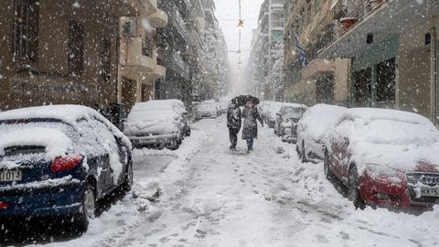 Menschen gehen in Athen bei Schneefall durch eine Straße