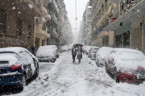 Menschen gehen in Athen bei Schneefall durch eine Straße