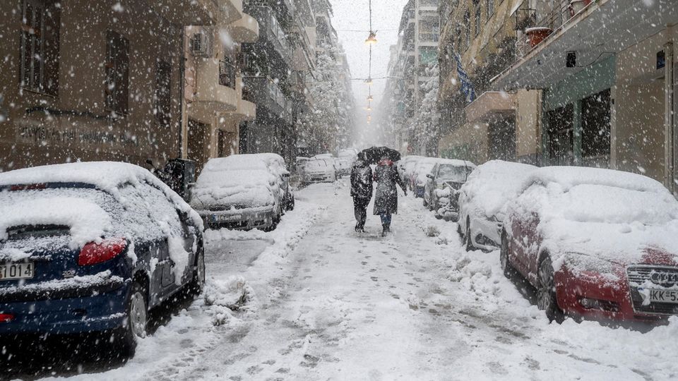 Menschen gehen in Athen bei Schneefall durch eine Straße Menschen gehen in Athen bei Schneefall durch eine Straße