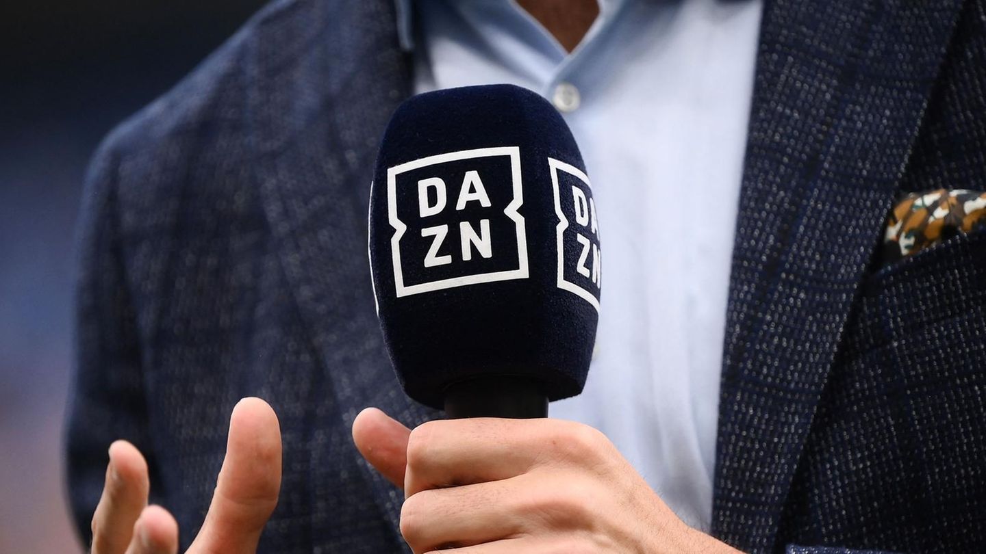 Ein Mann hält ein Mikrofon mit dem Logo von DAZN