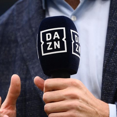 Ein Mann hält ein Mikrofon mit dem Logo von DAZN