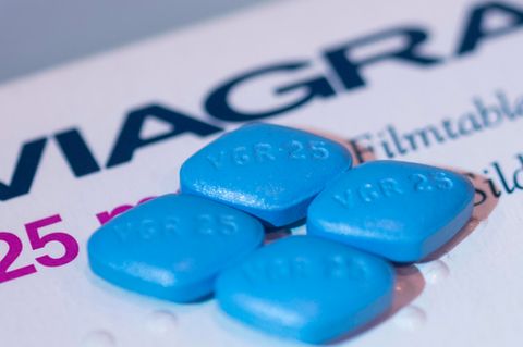 Vier Viagra-Tabletten liegen auf einer Viagra-Packung