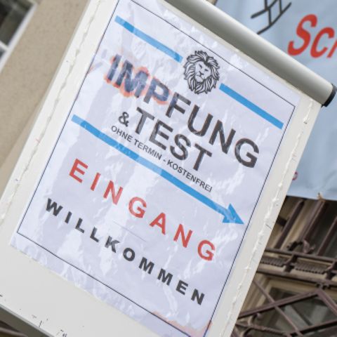 Impfpflicht-Debatte: Frau geht unter Plakat mit Aufschrift Corona-Impfung