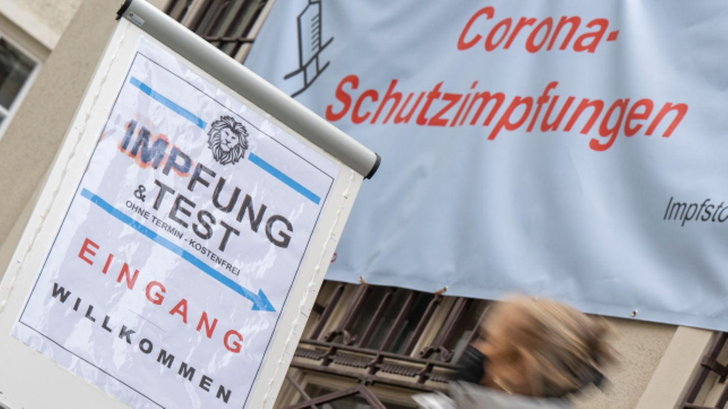 Impfpflicht-Debatte: Frau geht unter Plakat mit Aufschrift Corona-Impfung