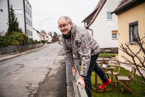 Axel Nagat steigt über den Zaun vor seinem Haus