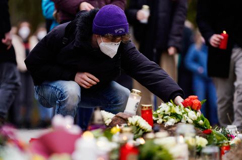Ein junger Mann legt Blumen zu den Kerzen für die Opfer des Amoklaufs in Heidelberg