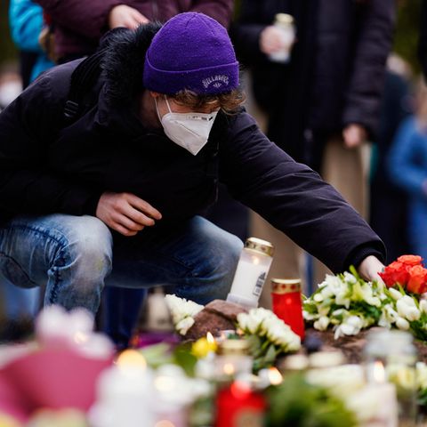 Ein junger Mann legt Blumen zu den Kerzen für die Opfer des Amoklaufs in Heidelberg