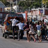 Menschen mit dunkler Haut laufen einem bunt bemalten Pickup hinterher für einen Platz auf der Ladefläche des Sammeltaxis