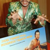 Mit längeren schwarzen Haaren zeigt sich Glööckler 2004. Vor ihm ein Plakat für die Tierschutzorganisation Peta, für das er sich unter den Slogan "Menschen tragen Mode, Tiere tragen Pelz" nackt fotografieren ließ.