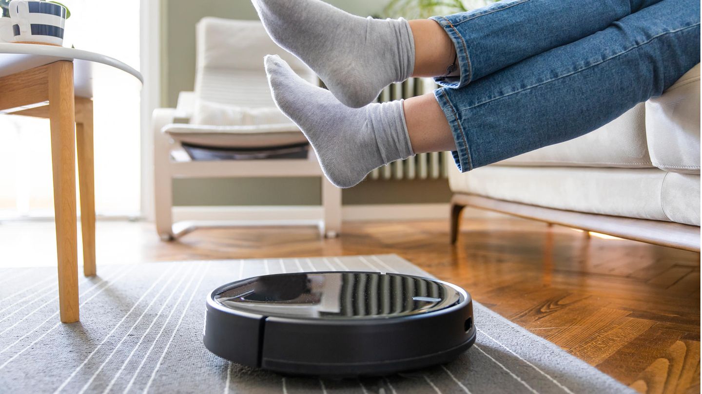 Ein Mensch hebt seine Füße über einen Saugroboter