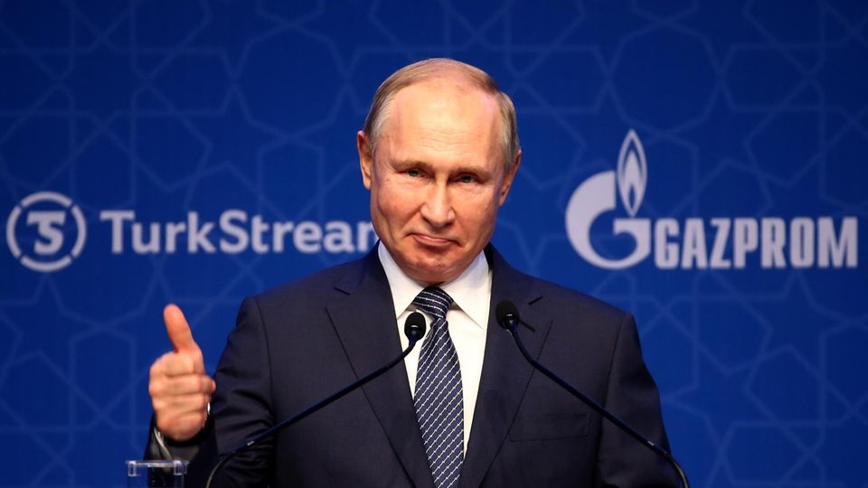 Russlands Präsident Wladimir Putin steht vor einem Podium und hält einen Daumen hoch