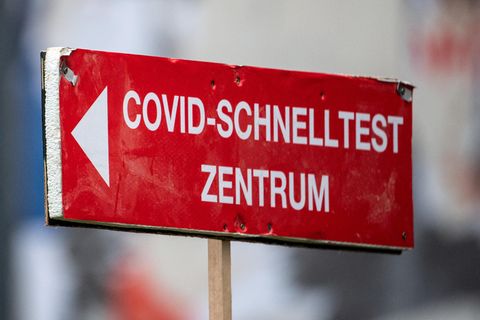 Ein roter Wegweiser mit weißer Schrift und Pfeil nach links weist auf ein Covid-Schnelltest-Zentrum hin