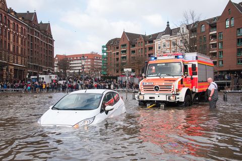 Ein weißer Kleinwagen steht am Hamburger Fischmarkt bis zur Hälfte der Türen in der über die Ufer getretene Elbe