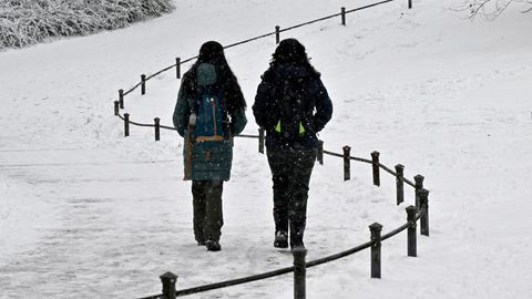 Passanten gehen durch einen verschneiten Park.