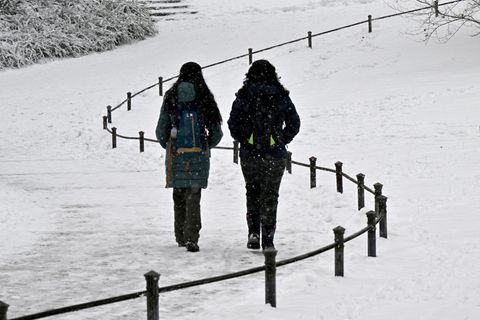 Passanten gehen durch einen verschneiten Park.