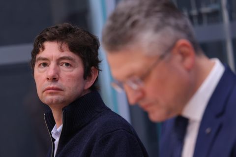 Ein weißer Mann mit dunkelbraunen Locken und ein weißer Mann mit grau-weißen Haaren und randloser Brille sitzen nebeneinander