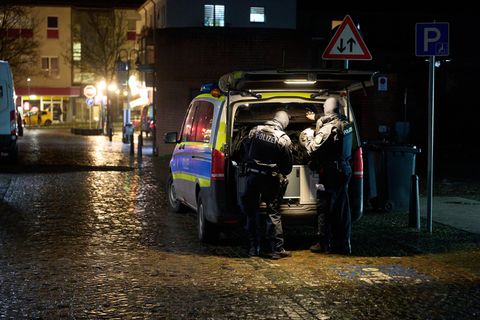 An der offenen Heckklappe eines silber-blauen Polizeibusses stehen zwei Menschen in dunkelblauen Uniformen und Schutzwesten