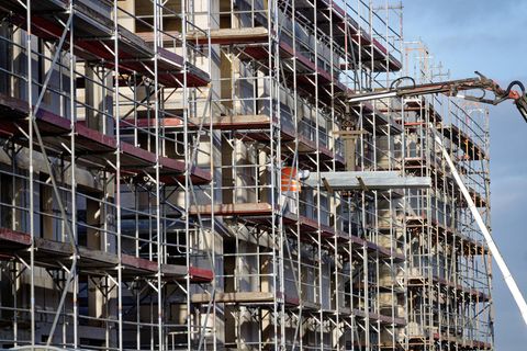 Eingerüstete, noch unfertige Neubauten stehen in einem Neubaugebiet in Hürth-Efferen. Nach dem plötzlichen KfW-Förderstopp bekommen viele Bauherren nun doch Geld für ihre energieeffizienten Häuser