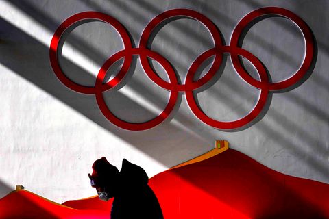Mann trägt Maske, während er vor Beginn der Wettkämpfe bei der Olympia 2022 in das Skisprungzentrum geht.