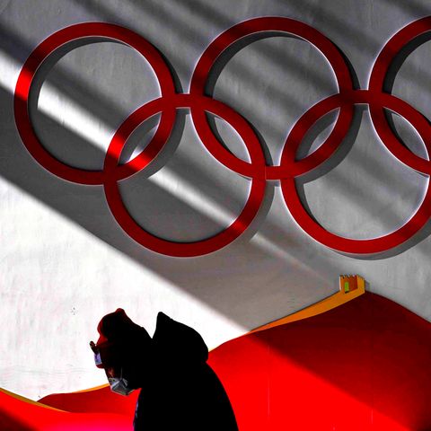 Mann trägt Maske, während er vor Beginn der Wettkämpfe bei der Olympia 2022 in das Skisprungzentrum geht.