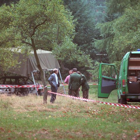 Polizeibeamte am 13.10.1991 bei der Spurensuche auf einem Waldparkplatz in Stukenbrock bei Bielefeld mit dem ausgebrannten Fahrzeug der vermissten Polizisten