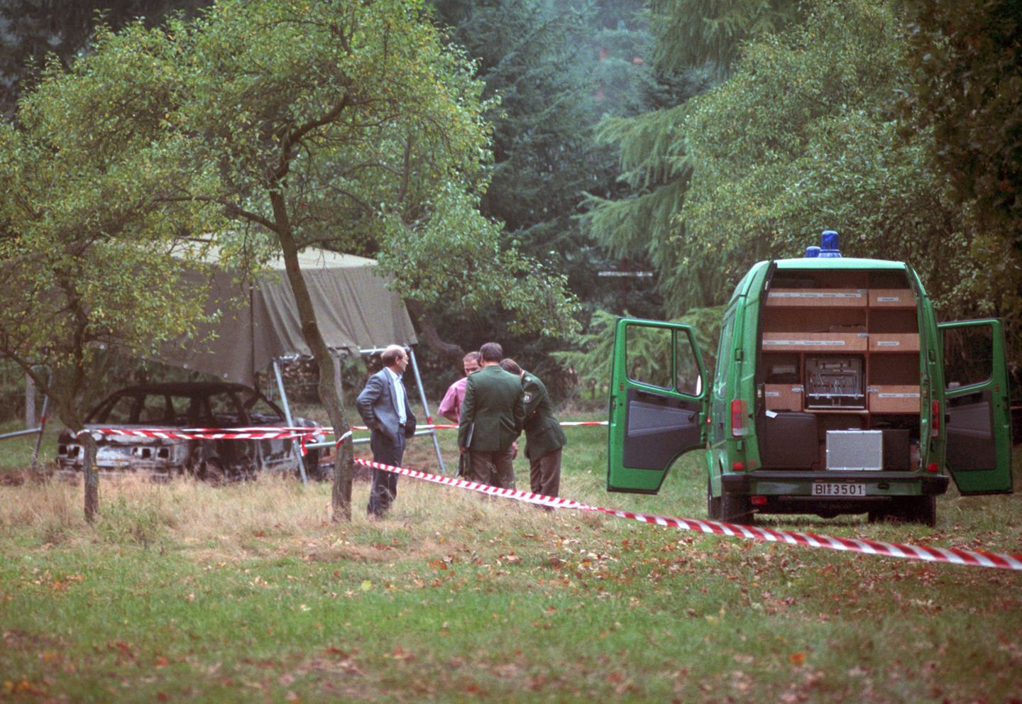 Polizeibeamte am 13.10.1991 bei der Spurensuche auf einem Waldparkplatz in Stukenbrock bei Bielefeld mit dem ausgebrannten Fahrzeug der vermissten Polizisten