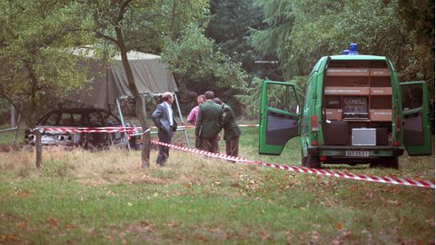 Polizeibeamte am 13.10.1991 bei der Spurensuche auf einem Waldparkplatz in Stukenbrock bei Bielefeld mit dem ausgebrannten Fahrzeug der vermissten Polizisten