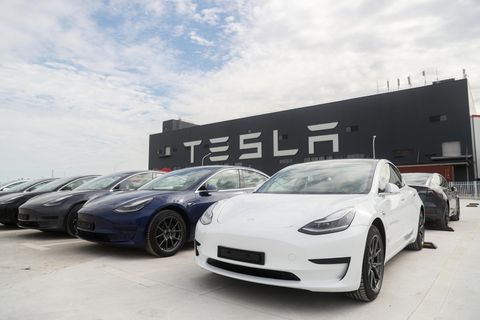 Fahrzeuge von Tesla stehen nebeneinander auf einem Parkplatz vor einem Geschäftsgebäude