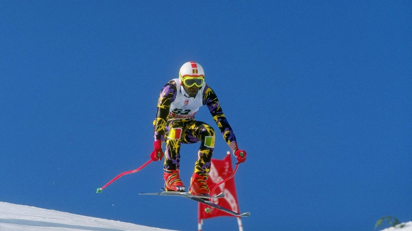 Winterspiele 2022: Lamine Guèye aus dem Senegal arbeitete als Model in Paris und fuhr in seiner Freizeit leidenschaftlich gern Ski. Daraus erwuchs offenbar die Idee, an den Olympischen Winterspielen 1984 in Sarajevo teilzunehmen, was auch klappte. Wie man sich denken kann, war der Erfolg eher bescheiden, aber darum geht Guèye nicht. Auch an den Spielen in Albertville 1992 und in Lillehammer 1994 nahm er teil. Seitdem setzt er sich als Präsident des senegalesischen Skiverbandes dafür ein, dass auch kleinere Länder ohne Ski-Tradition leichteren Zugang zu den Olympischen Spielen haben. Lamine Guèye aus dem Senegal arbeitete als Model in Paris und fuhr in seiner Freizeit leidenschaftlich gern Ski. Daraus erwuchs offenbar die Idee, an den Olympischen Winterspielen 1984 in Sarajevo teilzunehmen, was auch klappte. Wie man sich denken kann, war der Erfolg eher bescheiden, aber darum geht Guèye nicht. Auch an den Spielen in Albertville 1992 und in Lillehammer 1994 nahm er teil. Seitdem setzt er sich als Präsident des senegalesischen Skiverbandes dafür ein, dass auch kleinere Länder ohne Ski-Tradition leichteren Zugang zu den Olympischen Spielen haben.