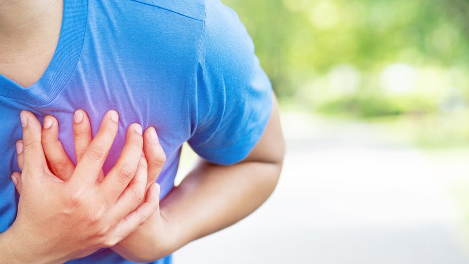 Herzmuskelentzündung nach Corona: Ein Mann hält seinen Brustkorb umklammert
