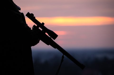 Ein Jäger hält sein Gewehr in der Abenddämmerung