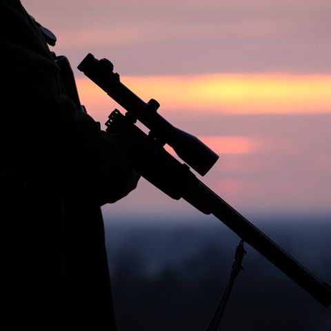 Ein Jäger hält sein Gewehr in der Abenddämmerung