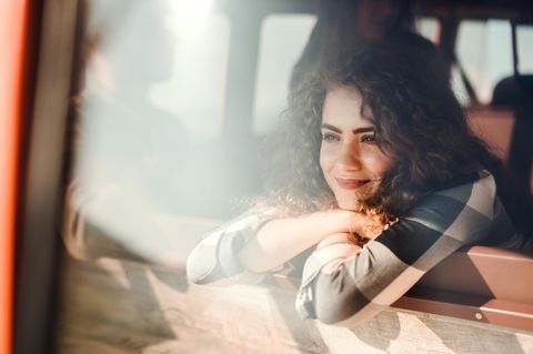 Frau schaut aus dem Fenster eines Autos und lächelt