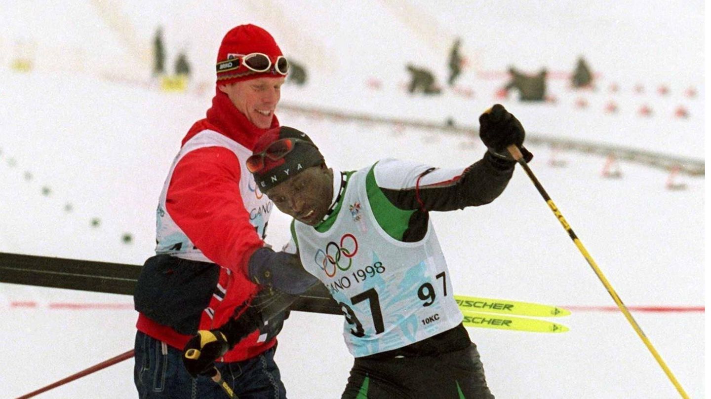 Winterspiele 2022: Auch wenn es die Marketing-Idee eines amerikanischen Sportartikel-Herstellers war, den Kenianer Philip Boit in die Loipe zu schicken, so verkörpert der Athlet doch geradezu vorbildlich die Idee des "Dabei sein ist alles". Als Mittelstreckenläufer über 800 Meter war Boid ziemlich gut, für die Weltspitze reichte es aber nicht. Also nahm er das Angebot des Sponsors an, im Skilanglauf anzutreten, obwohl er nie zuvor Schnee gesehen hatte. 1998 startete er bei den Spielen in Nagano und wurde im Langlauf über die 10 Kilometer weit abgeschlagen Letzter. Im Ziel gratulierte ihm der norwegische Superstar Bjørn Dæhlie (das Bild zeigt die Szene), was Boit weitere Werbeverträge und viel Prominenz einbrachte. Auch an den Spielen in Salt Lake City und Turin nahm er teil. Seinen Sohn benannte er mit Vornamen Dæhlie, eine seiner Töchter heißt Olympia. Auch wenn es die Marketing-Idee eines amerikanischen Sportartikel-Herstellers war, den Kenianer Philip Boit in die Loipe zu schicken, so verkörpert der Athlet doch geradezu vorbildlich die Idee des "Dabei sein ist alles". Als Mittelstreckenläufer über 800 Meter war Boid ziemlich gut, für die Weltspitze reichte es aber nicht. Also nahm er das Angebot des Sponsors an, im Skilanglauf anzutreten, obwohl er nie zuvor Schnee gesehen hatte. 1998 startete er bei den Spielen in Nagano und wurde im Langlauf über die 10 Kilometer weit abgeschlagen Letzter. Im Ziel gratulierte ihm der norwegische Superstar Bjørn Dæhlie (das Bild zeigt die Szene), was Boit weitere Werbeverträge und viel Prominenz einbrachte. Auch an den Spielen in Salt Lake City und Turin nahm er teil. Seinen Sohn benannte er mit Vornamen Dæhlie, eine seiner Töchter heißt Olympia.