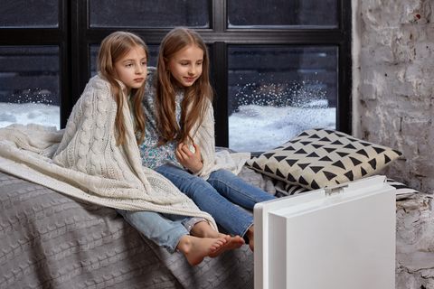 Kinder frieren mit einer Decke auf einem Bett