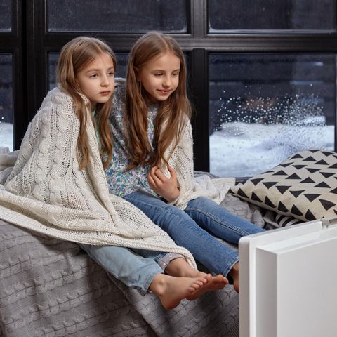 Kinder frieren mit einer Decke auf einem Bett