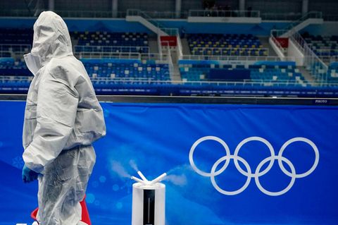 Mann im Schutzanzug passiert die Olympischen Ringe