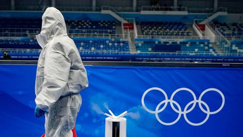 Mann im Schutzanzug passiert die Olympischen Ringe
