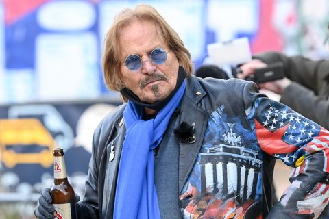 Frank Zander trägt eine bunte Lederjacke und hält eine Flasche Bier in der rechten Hand