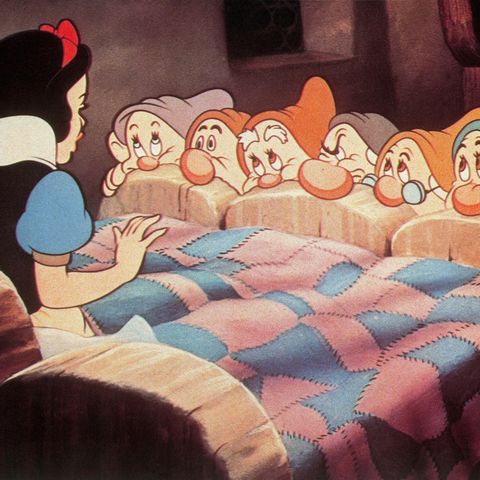 Schneewittchen sitzt auf dem Bett vor ihren sieben Zwergen