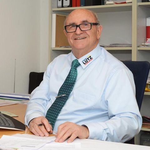 Lachender Mann mit Brille am Schreibtisch