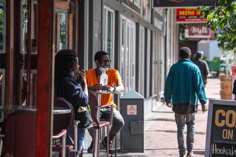 Corona in Südafrika: Menschen sitzen vor einer Bar in einer Einkaufsstraße.