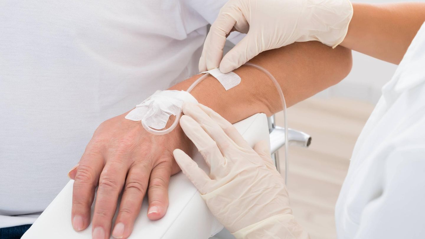 Doktor führt tropf in die Hand des Patienten ein