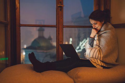 Eine Frau hat einen 14-Zoll-Laptop auf dem Schoß und schaut lächelnd auf den Bildschirm.