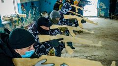 Freiwillige lernen bei einer militärischen Übung in einem Gebäude, wie man mit einem hölzernen Übungsgewehr zielt