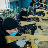 Freiwillige lernen bei einer militärischen Übung in einem Gebäude, wie man mit einem hölzernen Übungsgewehr zielt