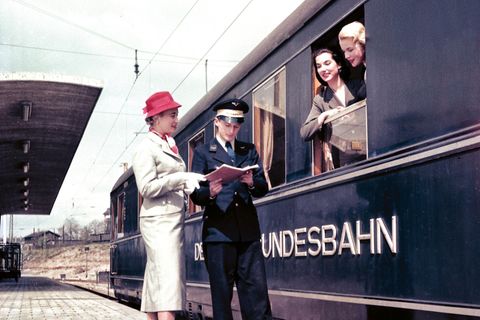 Werbemotiv der Bahn aus den späten 1950er Jahren: Fotomodelle am Fenster eines blauen Schürzenwagens für den Schnellzugverkehr  im Heidelberger Hauptbahnhof.