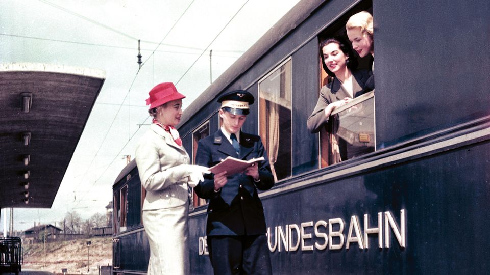Werbemotiv der Bahn aus den späten 1950er Jahren: Fotomodelle am Fenster eines blauen Schürzenwagens für den Schnellzugverkehr  im Heidelberger Hauptbahnhof.